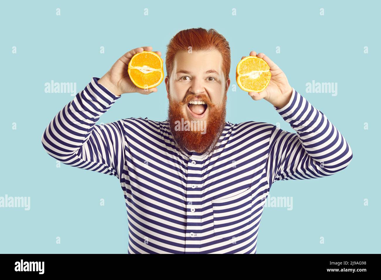 Lustig glücklich fetten Mann, der gerne frisches Obst isst, hält zwei orange Hälften und lächelt Stockfoto