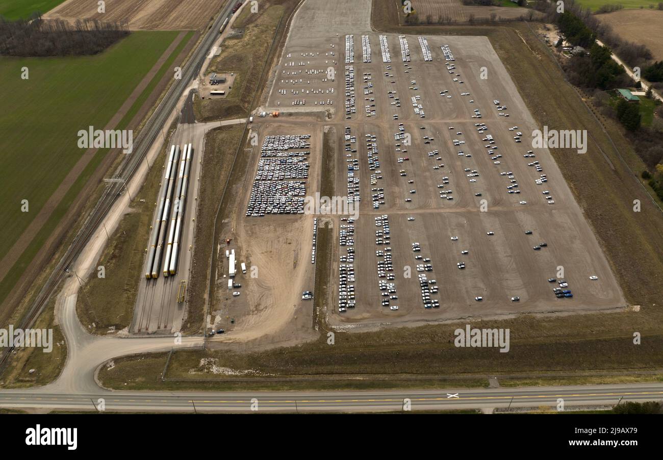 Eine Drohnenansicht neben einem Autodistributions- und Homologationszentrum. AutoTrack-Züge sitzen neben dem großen Zentrum, neben einer Eisenbahn. Stockfoto