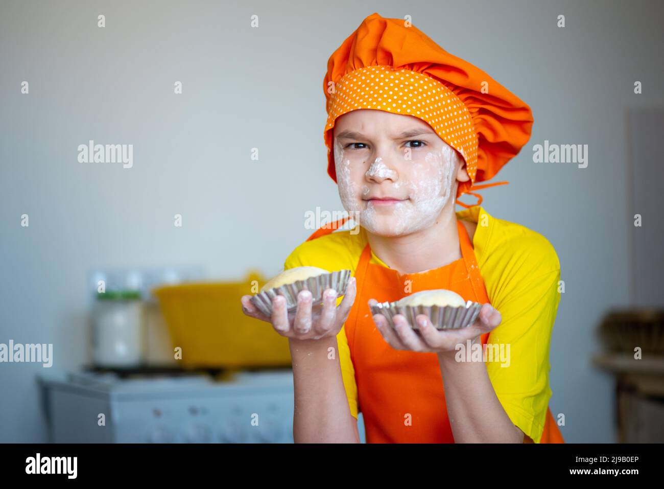 Ein Junge, der als Koch gekleidet ist, bereitet in der Küche Osterkuchen zu Stockfoto