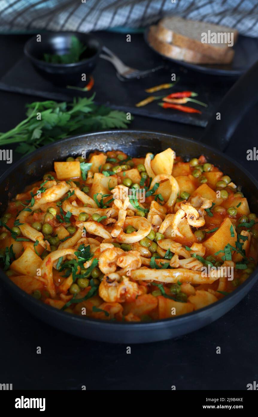 Geschmorte Tintenringe mit Erbsen und Kartoffeln in einer Pfanne ...