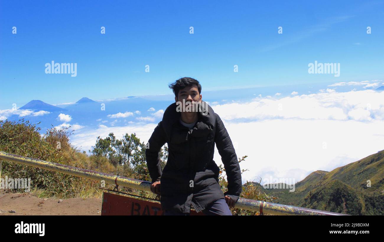 Magelang, Indonesien - 06 08 2019: Mann, der die Aussicht vom Gipfel des Mount Merbabu, Magelang, Zentral-Java, genießt Stockfoto