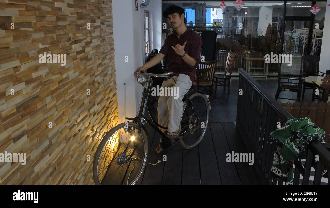 Yogyakarta, Indonesien - 08 07 2019: Der Ausdruck eines Mannes, der im Urlaub in Yogyakarta, Zentral-Java, ein altes Indoor-Fahrrad fährt Stockfoto