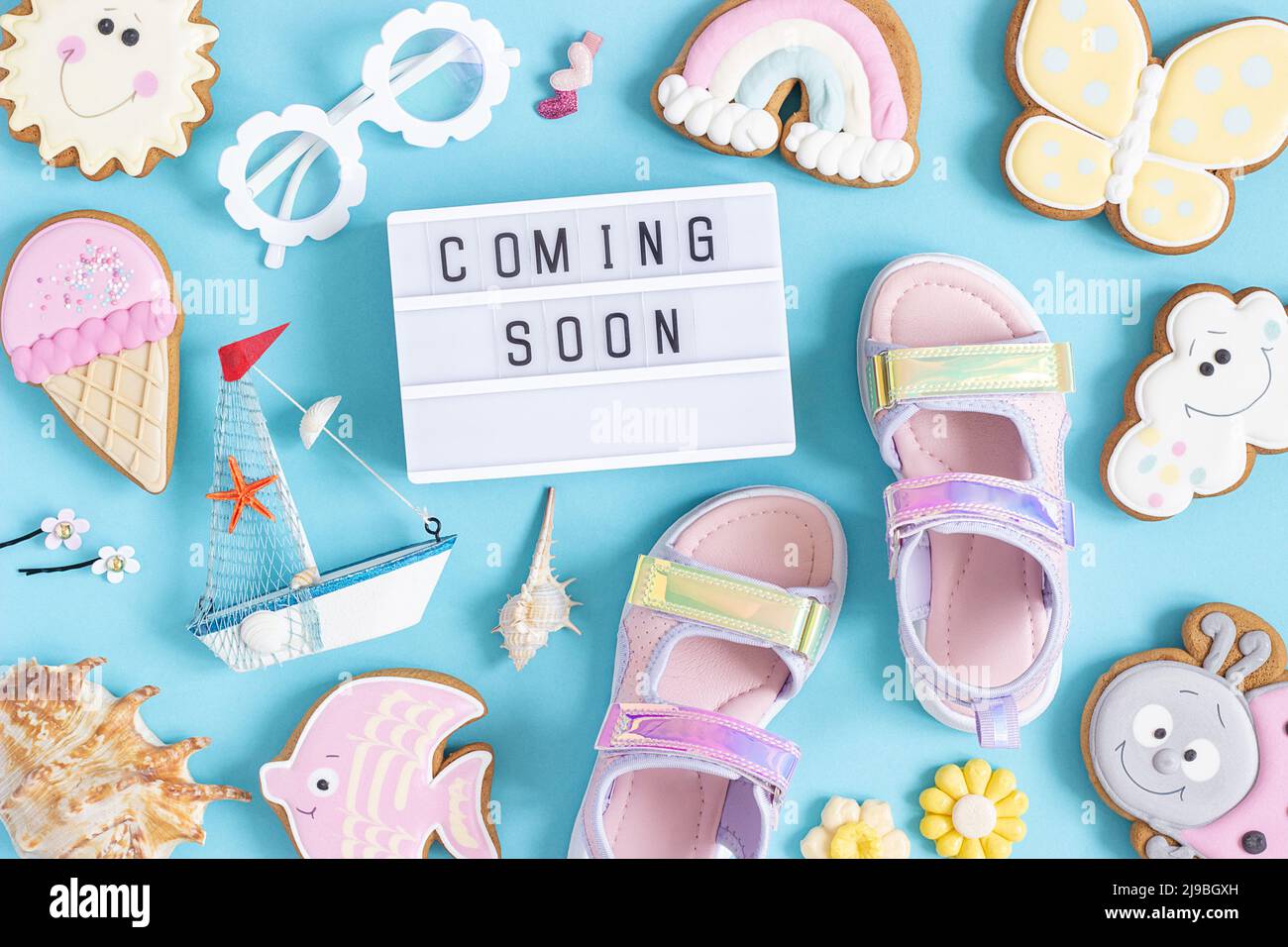 Demnächst verfügbar. Motivationszitat auf Leuchtkasten und niedlichen Sommer-Symbolen auf blauem Hintergrund. Draufsicht, Flat Lay. Kreatives, inspirierendes Sommerkonzept. Stockfoto