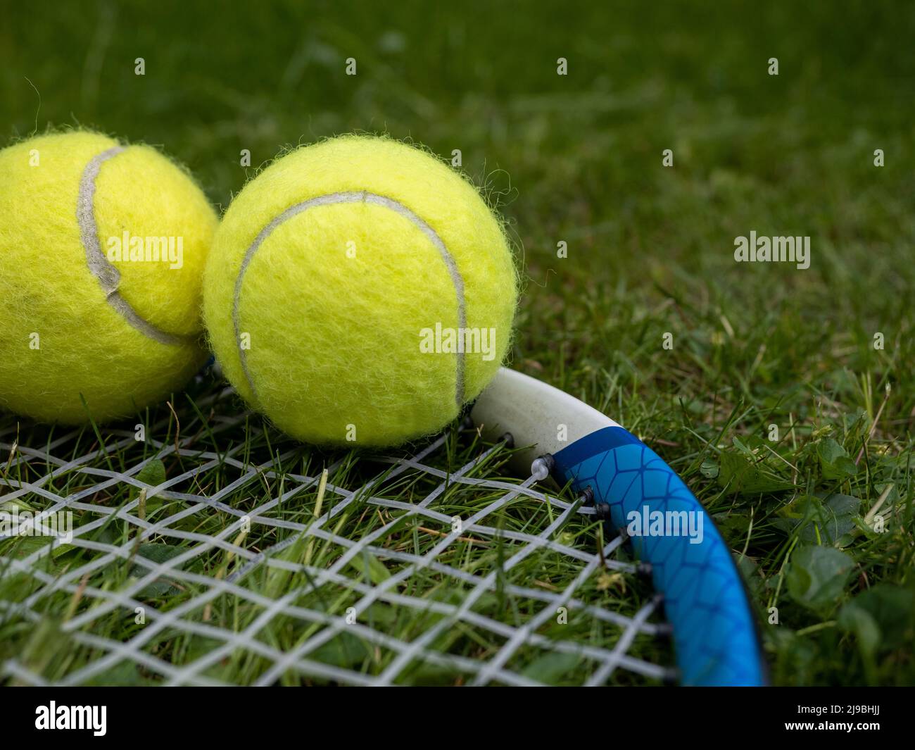 Nahaufnahme ausgewählter Fokus von Carbon leichten Tennisschläger Darmsaiten und Tennisbällen auf einem Rasenplatz Stockfoto