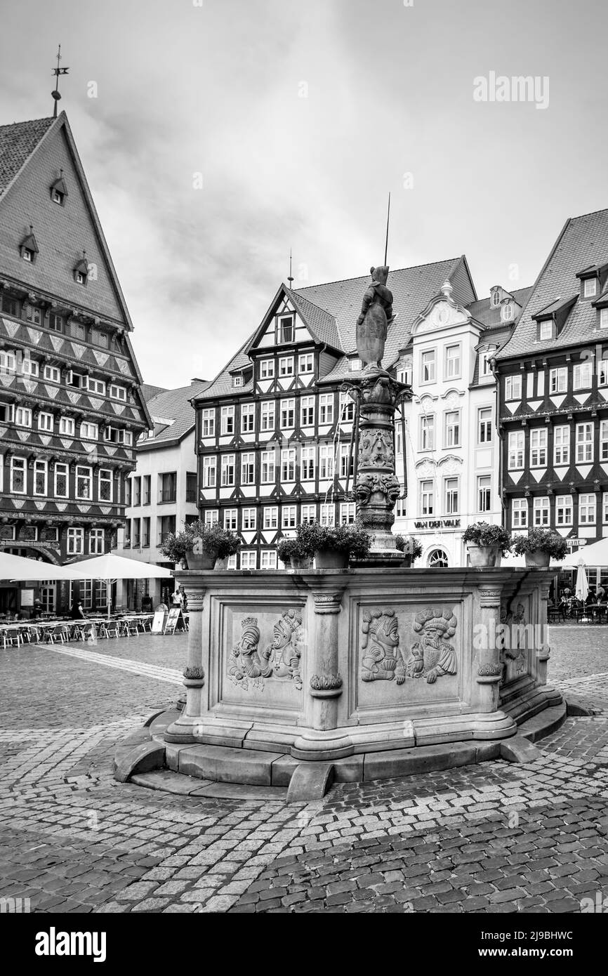 Hildesheim, Deutschland - 16. August 2012: Historische Gebäude und mittelalterlicher Brunnen auf dem Marktplatz in Hildesheim. Schwarz-weißes Stadtbild Stockfoto