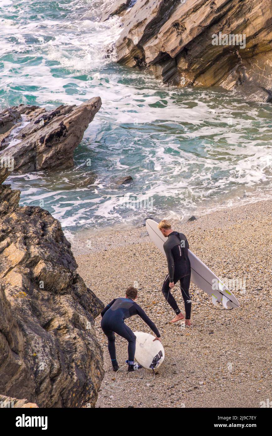 Surfer, die ihre Surfbretter tragen, betreten das Meer bei Little Fistral in Newquay in Cornwall. Stockfoto