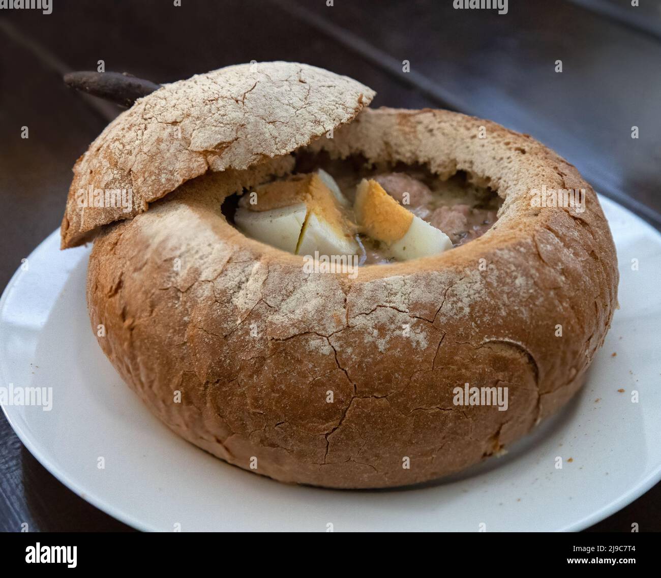 Weiße polnische Borschtsuppe mit Ei in Brotschale auf weißem Teller Stockfoto