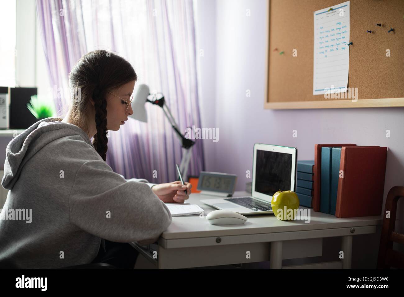 Eine Schülerin sitzt an ihrem Schreibtisch und macht Schularbeiten. Stockfoto