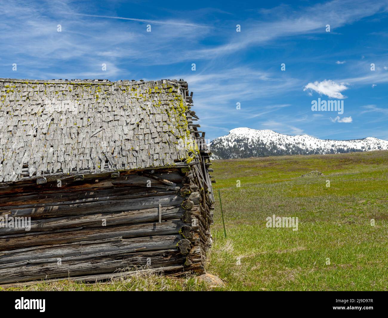 Schneebedeckter Berg hinter einer rustikalen Blockhütte im ländlichen Idaho Stockfoto