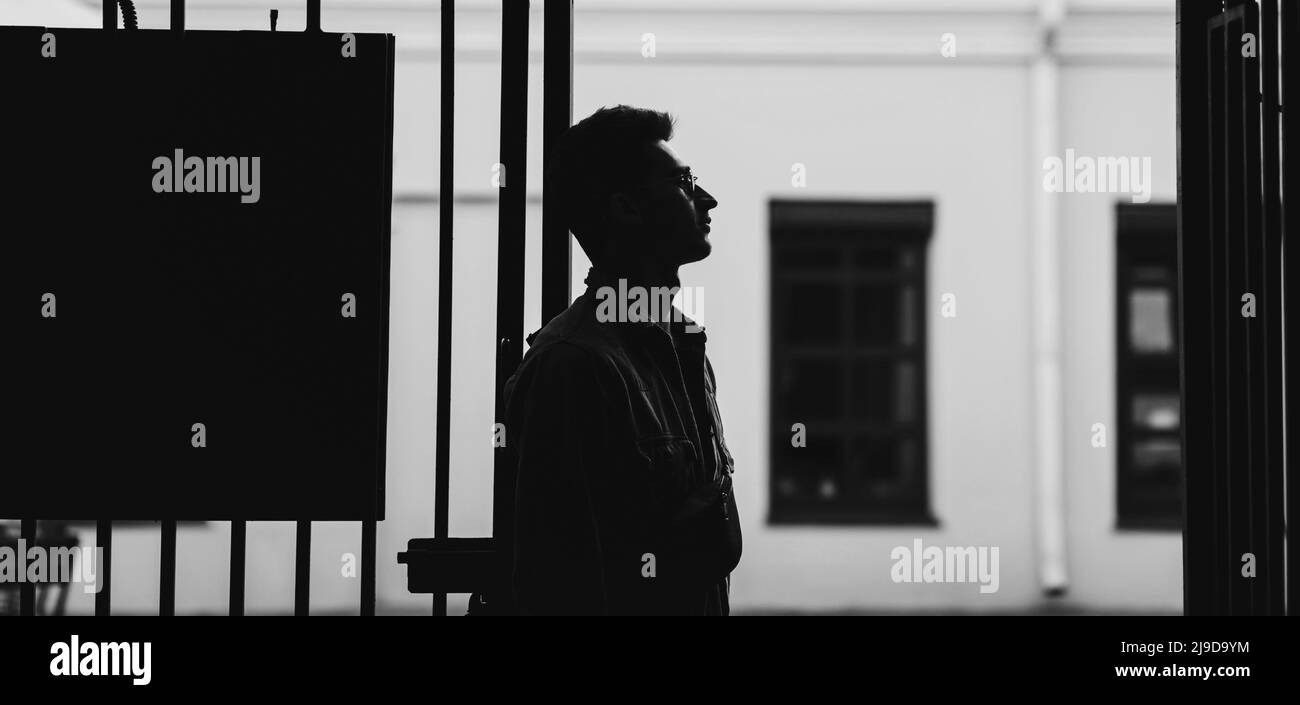 Porträt eines stylischen Mannes in einer Jeansjacke. Silhouette eines Mannes mit Brille Stockfoto