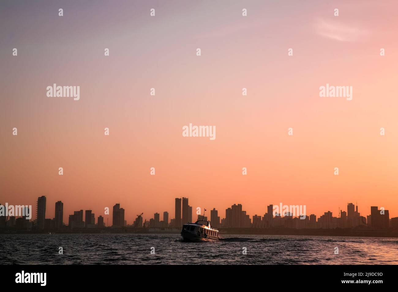 Blick auf den Sonnenaufgang am Flussufer auf die Skyline von Belém do Pará, der Metropole des brasilianischen Amazonas, mit einem kleinen Fährschiff im Vordergrund. Juli 2008. Stockfoto