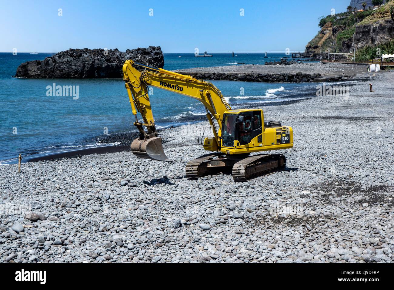 Ein Komatsu DC210 Bagger, der Steine an der Küste von San Martinho, Madeira, abflacht. Stockfoto