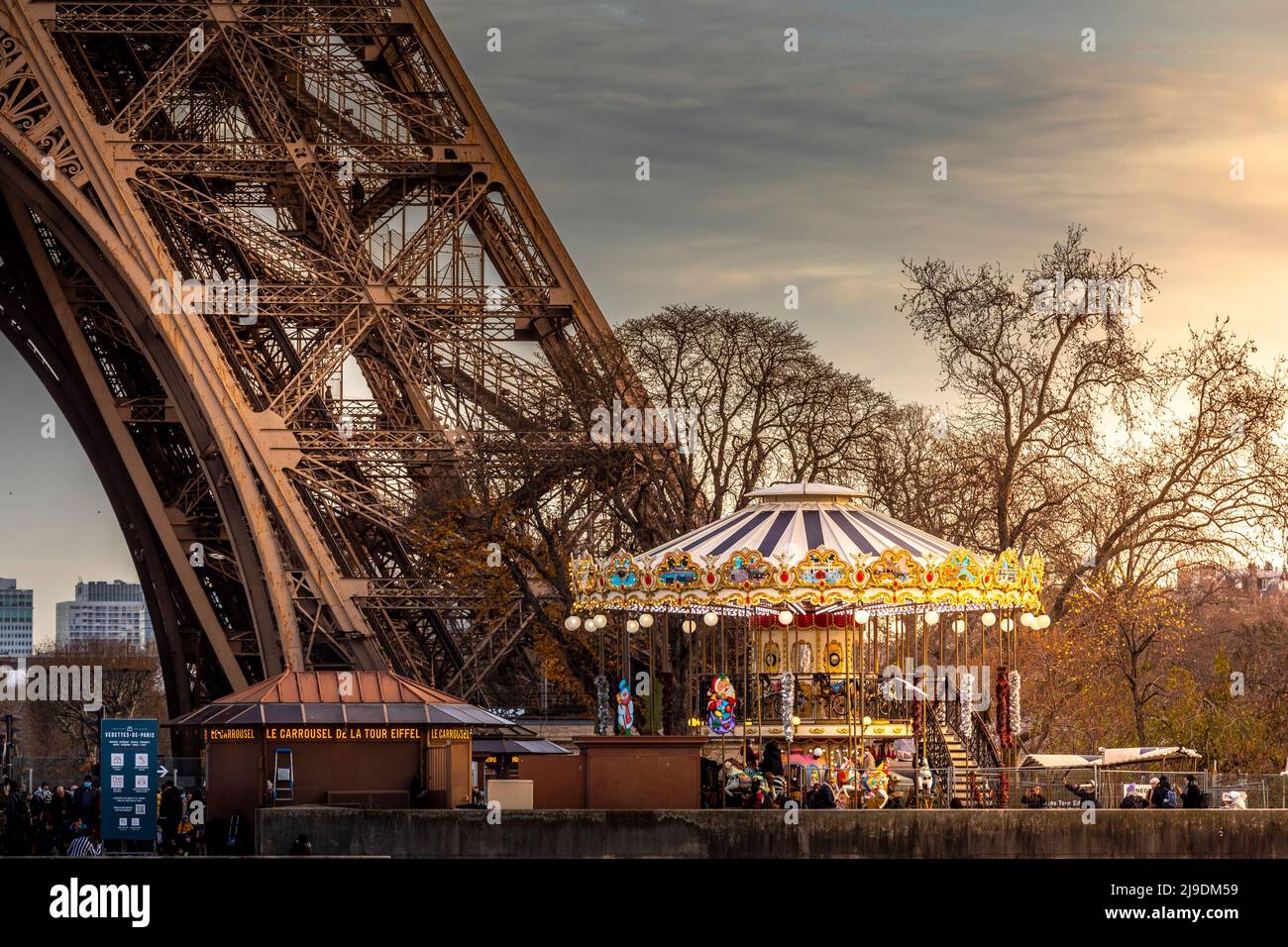 Paris, Frankreich - 11. Dezember 2021: Typisches Karussell vor dem Eiffelturm bei Sonnenuntergang in Paris Stockfoto