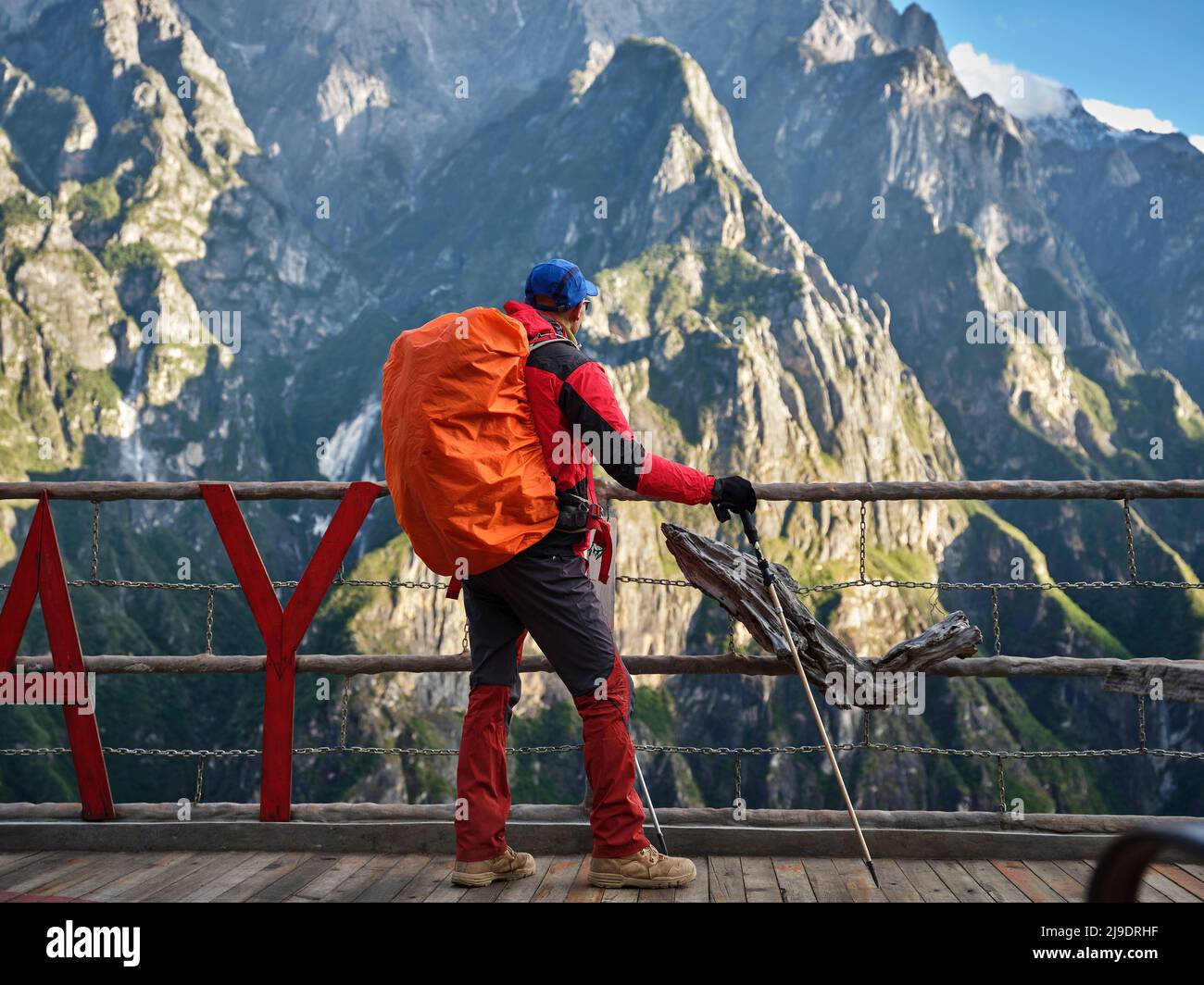 Rückansicht des asiatischen Wandertrekers mit Spazierstock, der auf der Aussichtsplattform steht und auf den Berg blickt Stockfoto