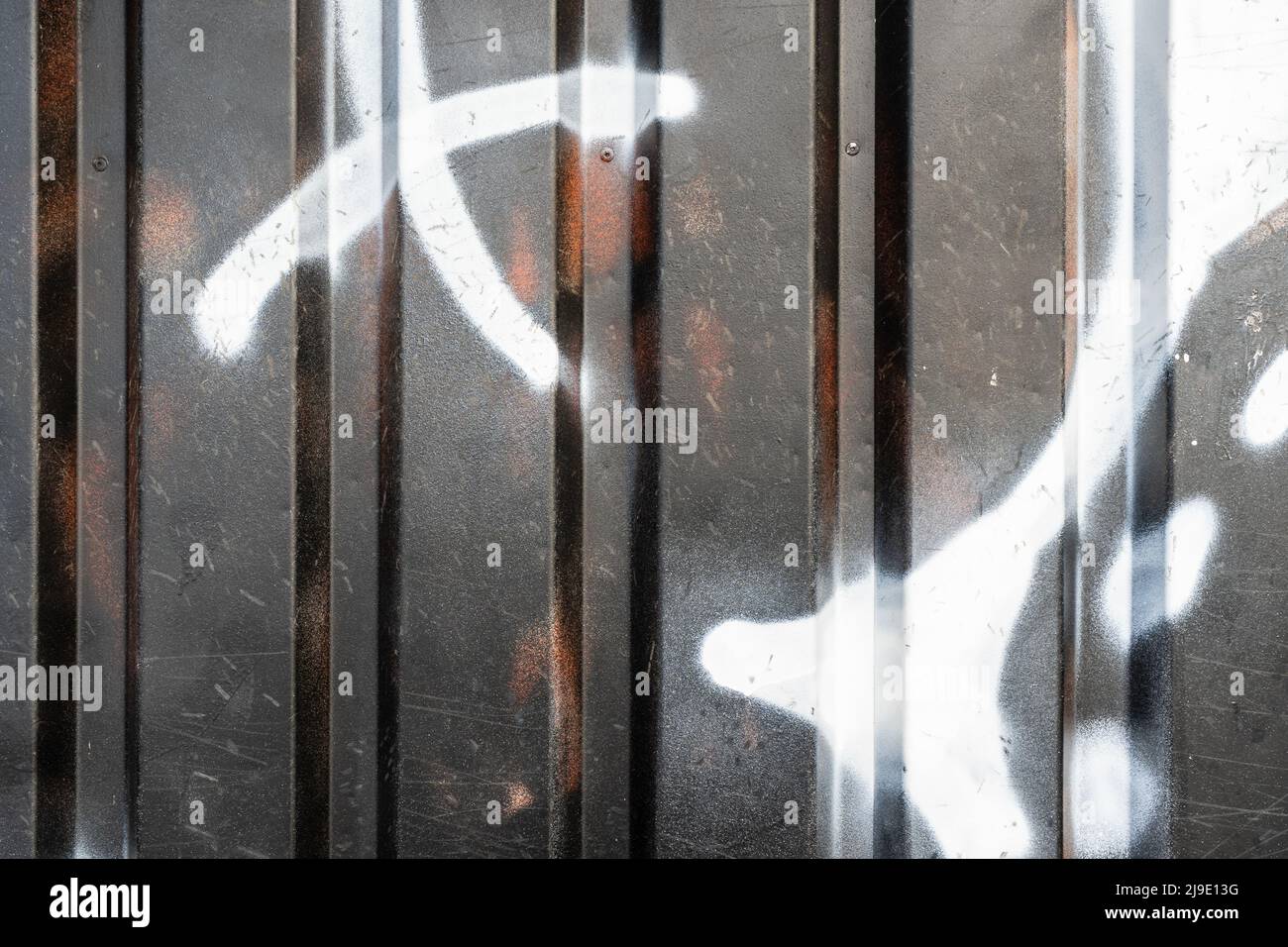 Graffiti auf Metallprofilen an einer Wand. Stockfoto