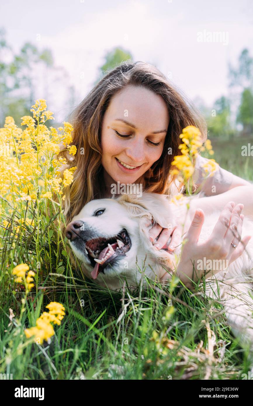 Junge schöne Frau und ihr goldener Retriever Hund haben Spaß im Sommer Stockfoto