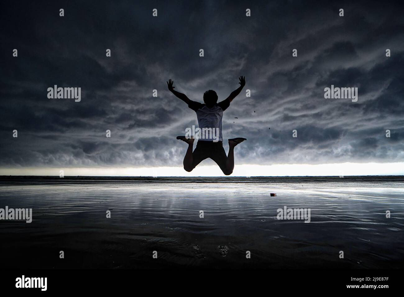 Ein Mann springt, während er für Fotos am Meer von Udaipur Beach, Digha (ca. 200 km von Kalkutta) mit einer dramatischen Wolkenlandschaft posiert. Das India Meteorological Department (IMD) hat vorhergesagt, dass der Monsunregen aufgrund der Auswirkungen der zwei Zyklone Asani und Karim voraussichtlich eine Woche zu Beginn dieses Jahres eintreffen wird. (Foto von Avishek das / SOPA Images/Sipa USA) Stockfoto