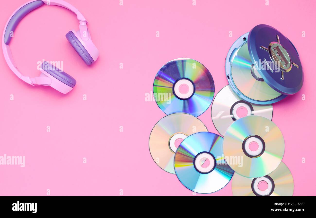 Der persönliche kompakte tragbare CD-Player ist mit violetten Kopfhörern auf einem rosa Hintergrund ausgestattet. Stockfoto
