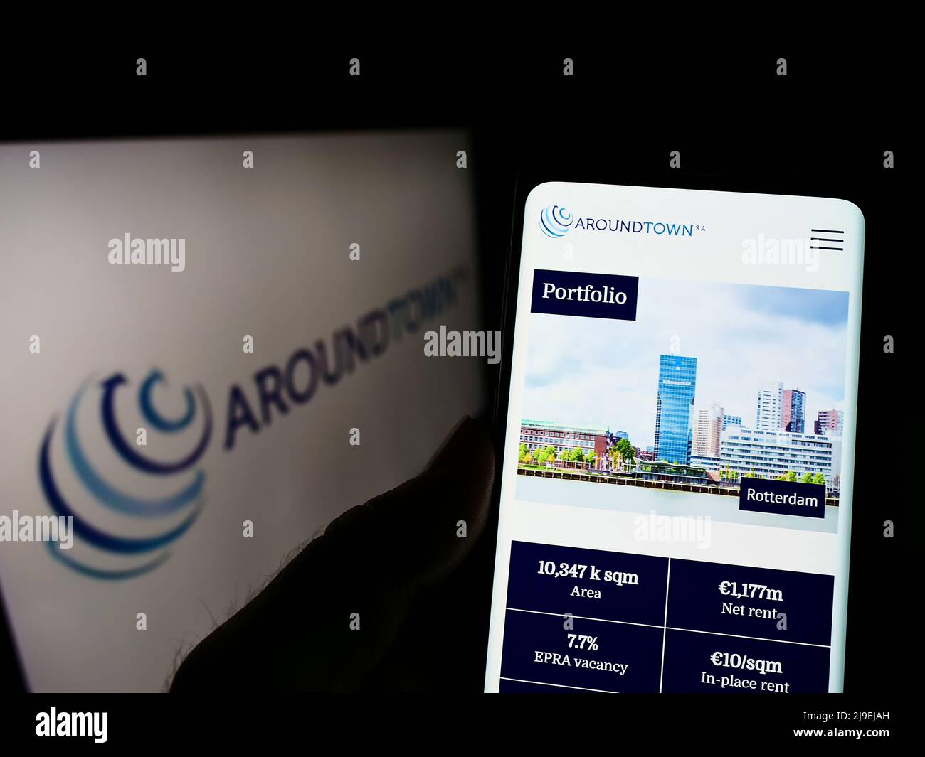 Person, die Smartphone mit der Webseite des Immobilienunternehmens Aroundtown SA auf dem Bildschirm vor dem Logo hält. Konzentrieren Sie sich auf die Mitte des Telefondisplays. Stockfoto