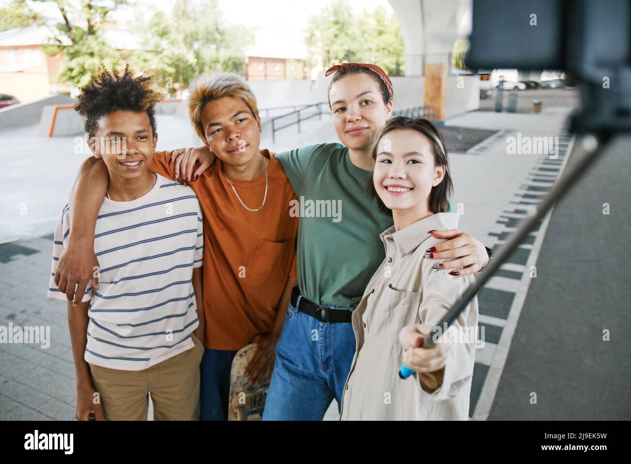 Diverse Gruppe von Teenagern, die im Stadtgebiet mit einem Selfie-Stick Selfie-Fotos machen Stockfoto