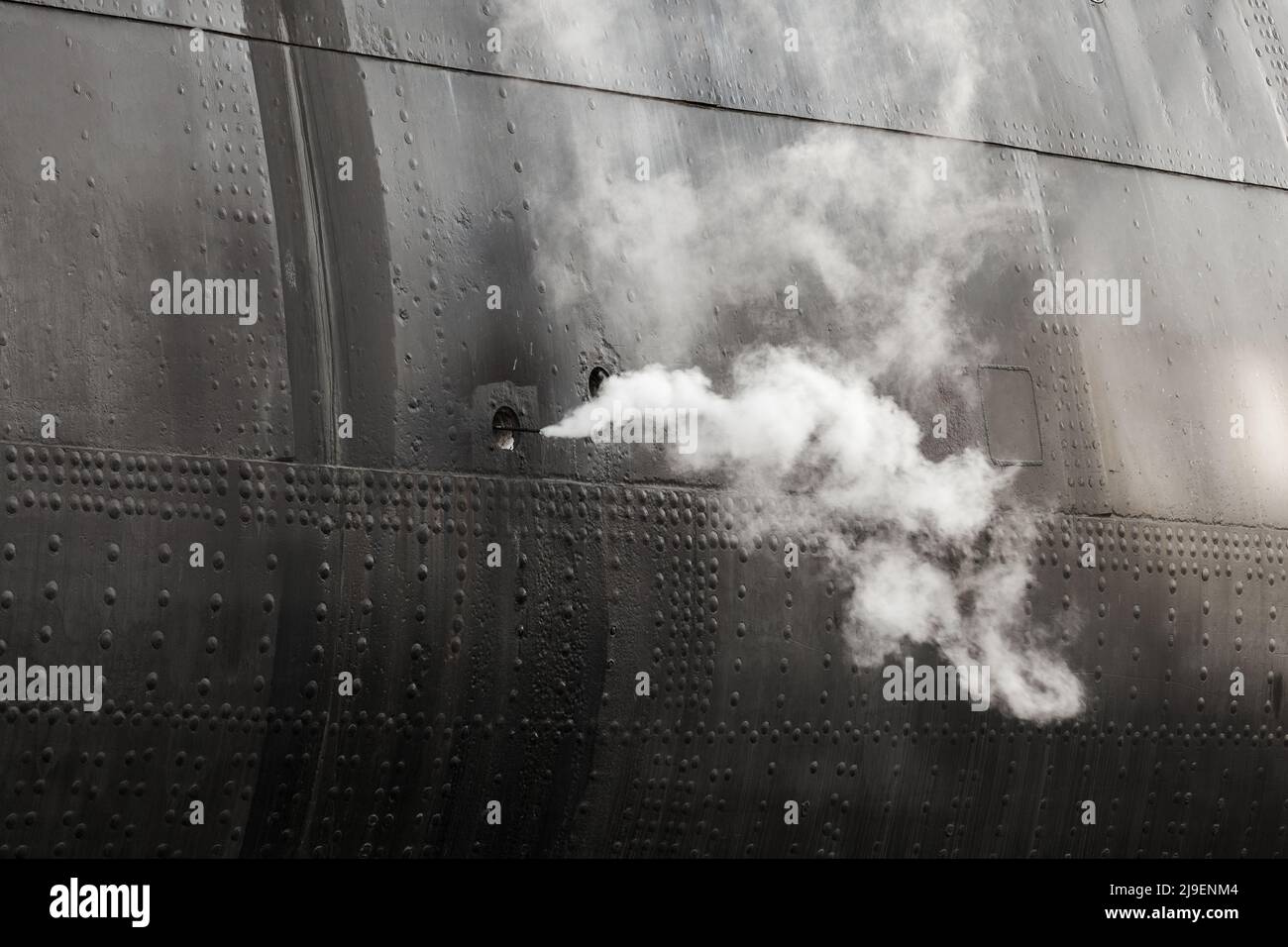 Dampf geht aus dem schwarzen alten Schiffsrumpf, abstraktes Industriefoto Stockfoto