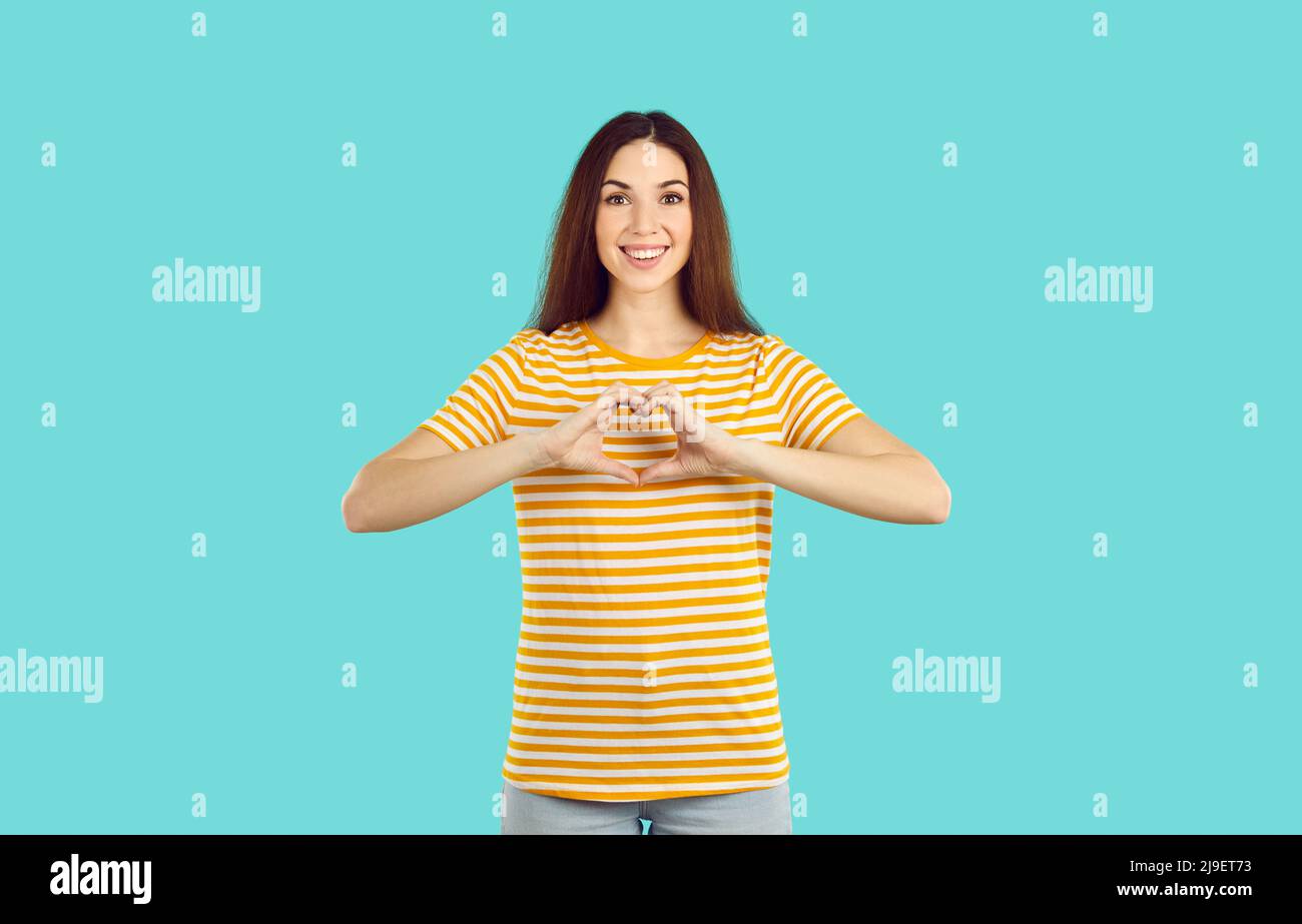 Lächelnde Frau zeigt eine Geste der Herzhand Stockfoto
