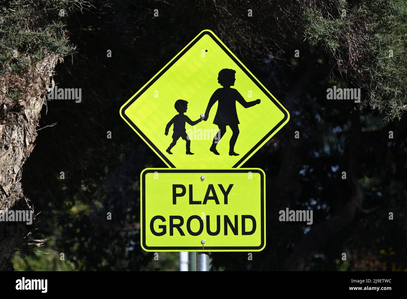 Ein Warnschild warnt den Fahrer, dass sich ein Spielplatz in der Nähe befindet, mit einem Symbol oder einer Grafik, die Mutter und Kind darstellt Stockfoto