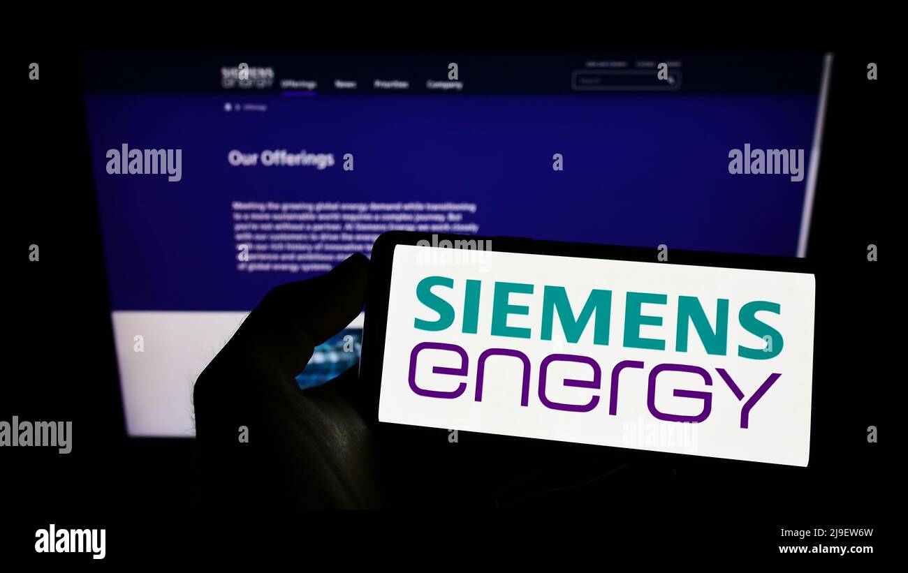 Person, die Mobiltelefon mit Logo des deutschen Technologieunternehmens Siemens Energy AG auf dem Bildschirm vor der Business-Webseite hält. Konzentrieren Sie sich auf die Telefonanzeige. Stockfoto