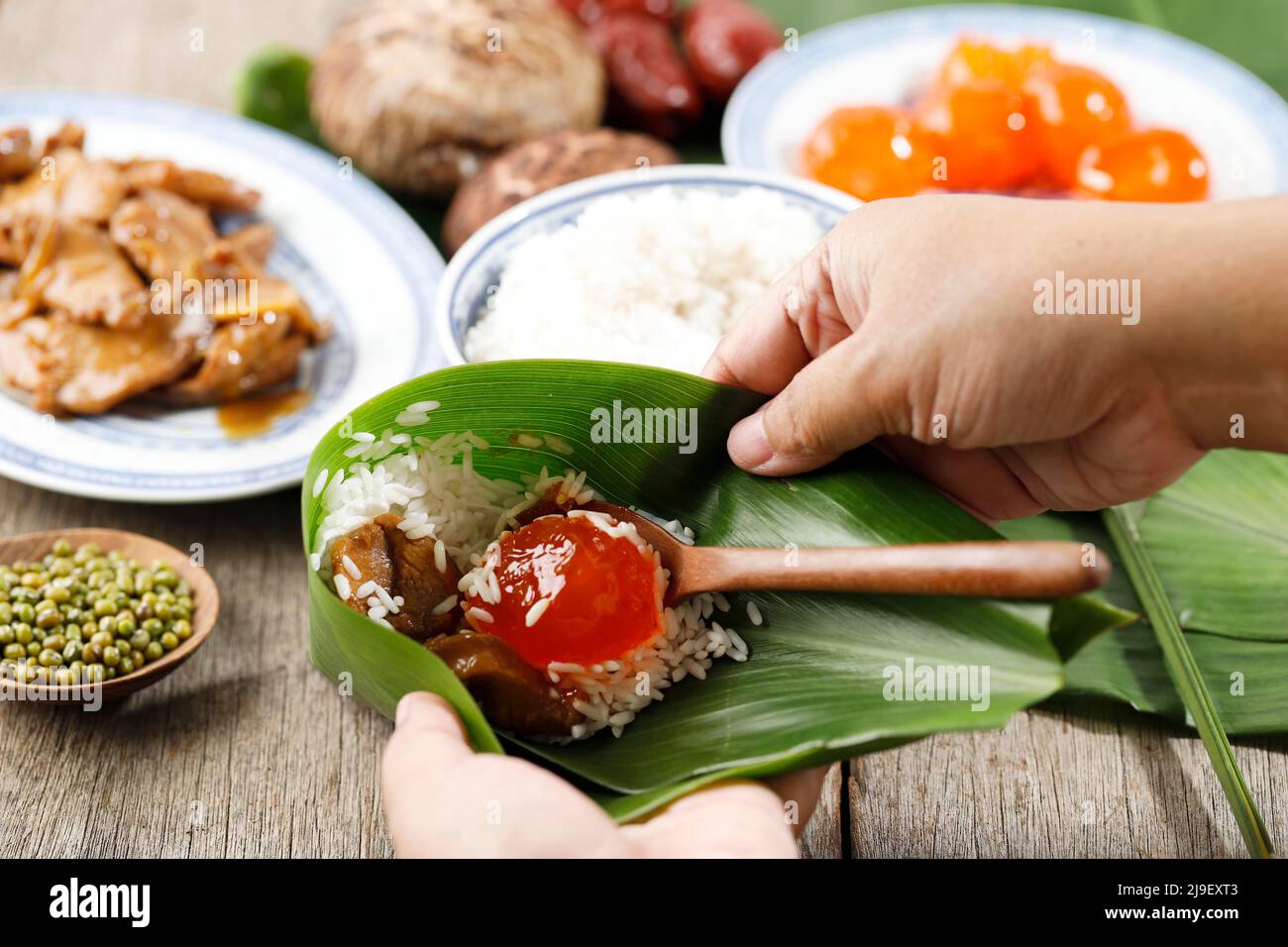 Lifestyle Shoot Reisknödel Bacang Zongzi Making, Wrapping Chinese Put Salted Egg Yolk on Ries for Dragon Boat Festival Feier, Close Up Stockfoto