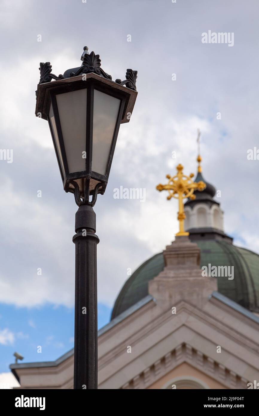 Antike Straßenlampe vor dem Hintergrund der Kuppel der orthodoxen Kirche. Stockfoto