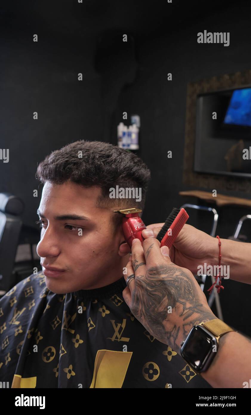 Junger Mann im Friseurladen, der im dunklen Vintage-Geschäft Haare schneidet Stockfoto