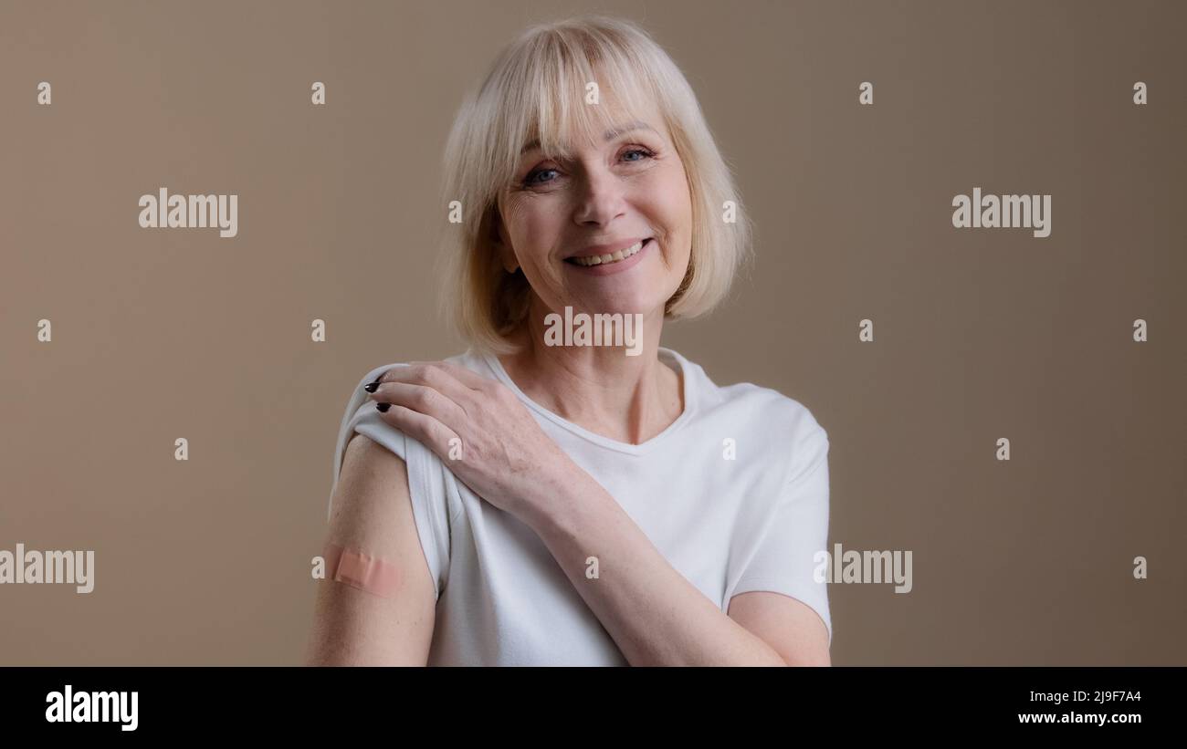 Coronavirus-Immunisierung Infektion covid19 Impfung glücklich geimpft ältere Dame Frau posiert mit Klebstoff medizinischen Putz auf Arm nach Stockfoto