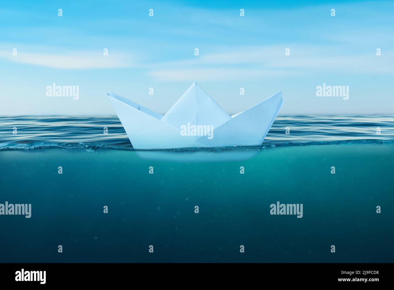 Papierboot auf der Meeresoberfläche. Blick unter das Meer. Das Konzept von Mut und Tapferkeit im Leben und das Risiko, schlechte Entscheidungen zu treffen, die ein shi sinken können Stockfoto