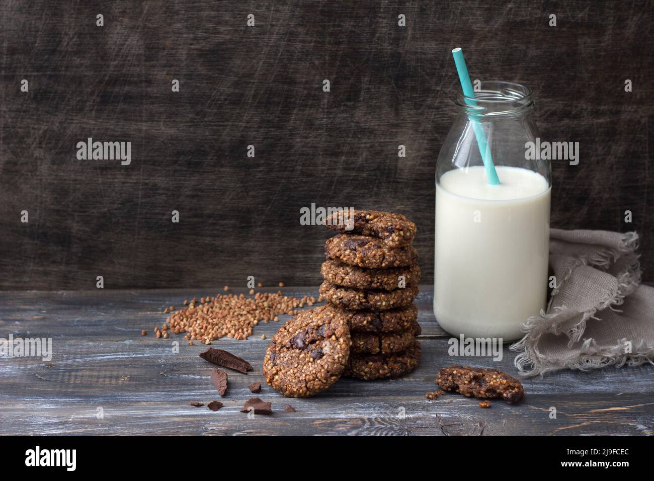 Gesunde glutenfreie Buchweizenkekse mit Schokolade und einer Flasche Milch auf einem Holztisch, Platz Stockfoto