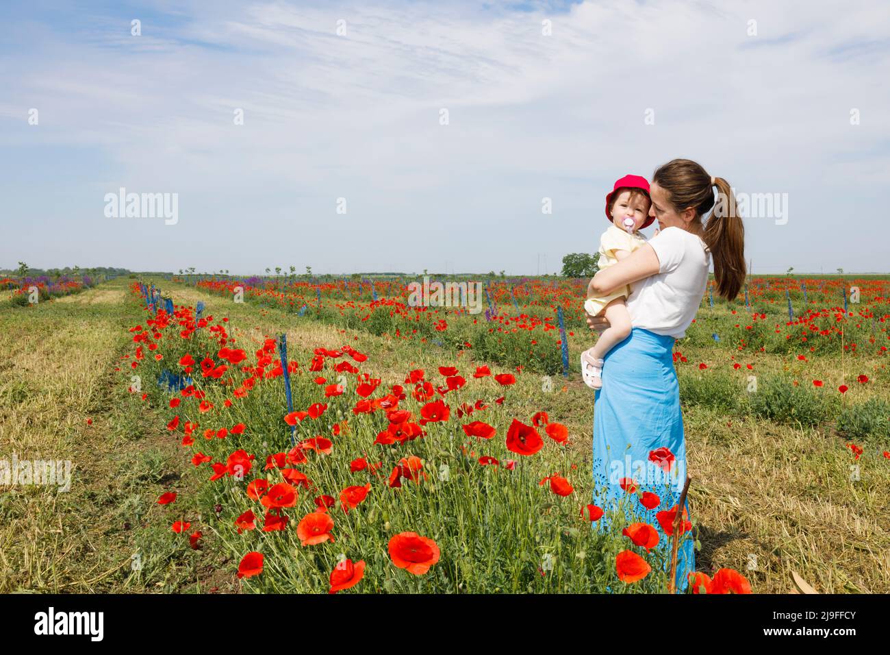 Eine Frau und ihre Tochter stehen auf einem roten Mohnfeld zusammen Stockfoto