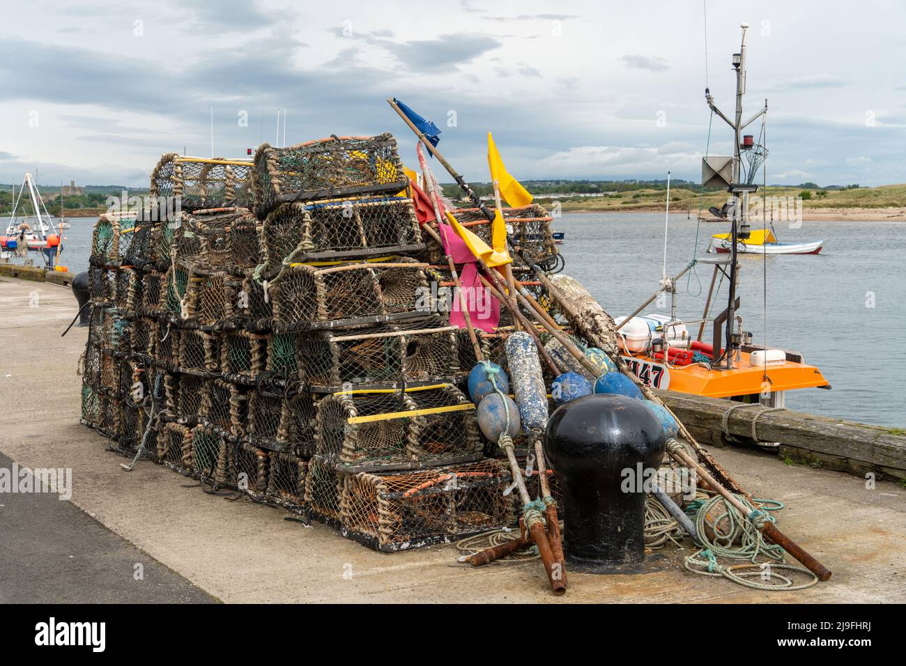Krabben- oder Hummertöpfe und andere Fischereigeräte am Hafen in Amble, Northumberland, Großbritannien. Stockfoto