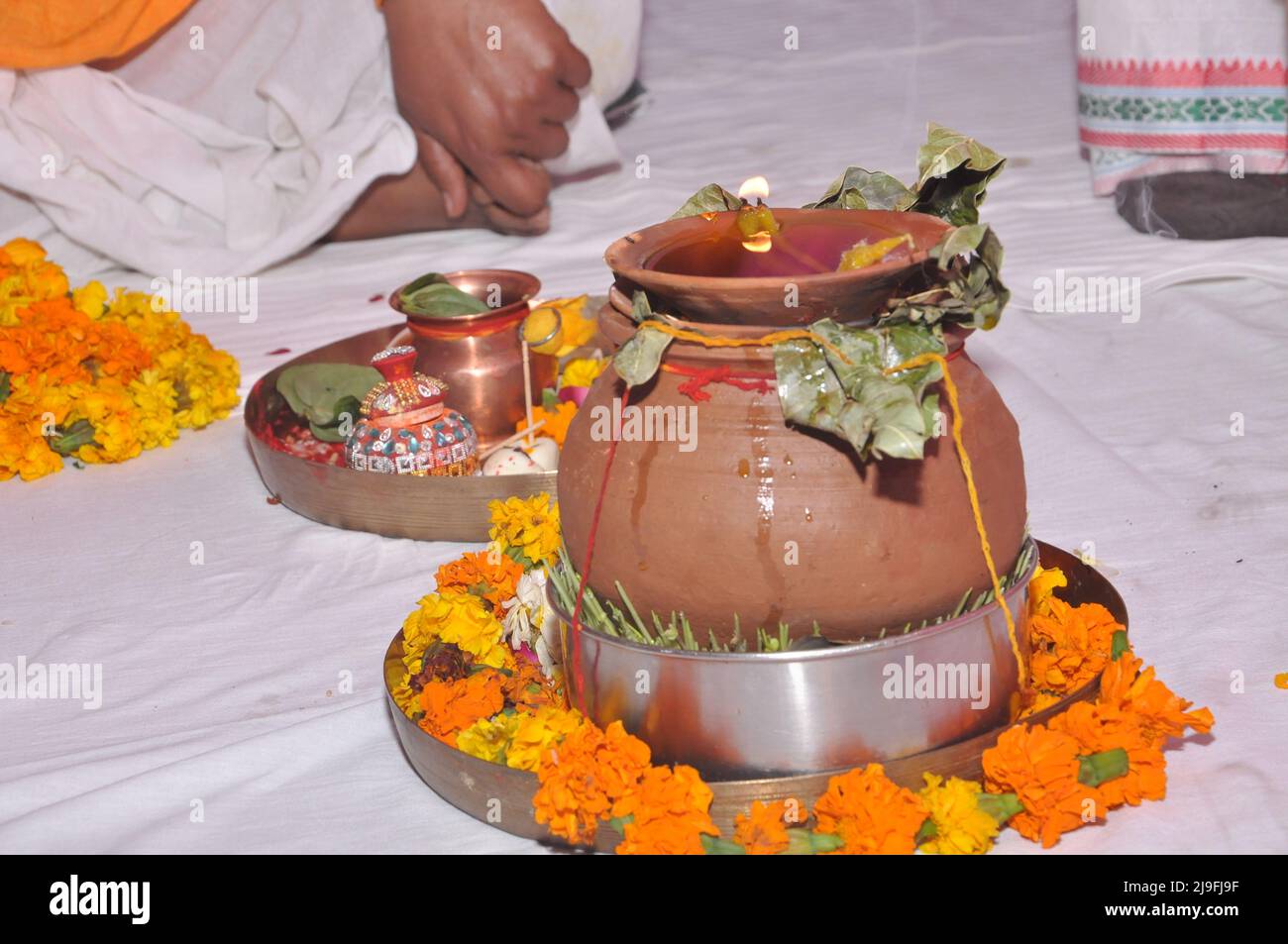 Indisches Hochzeitsritual mit Diya, kalash, Pooja thali und gelben Blumen Stockfoto
