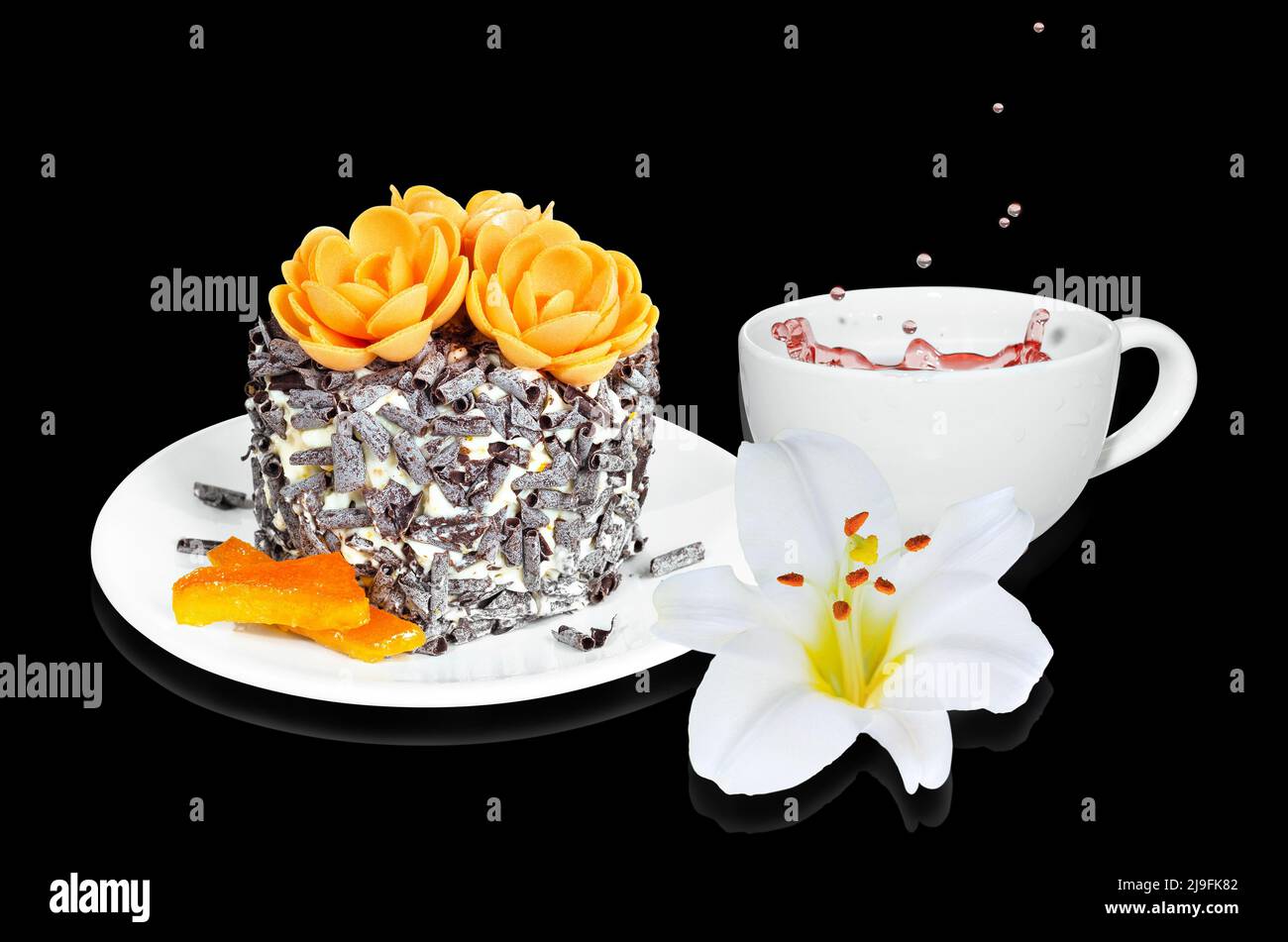 Ein kleiner Kuchen mit kandierten Orangen- und Schokoladenstückchen, einer Tasse Tee und einer Blume auf schwarzem Hintergrund. Selektiver Fokus Stockfoto