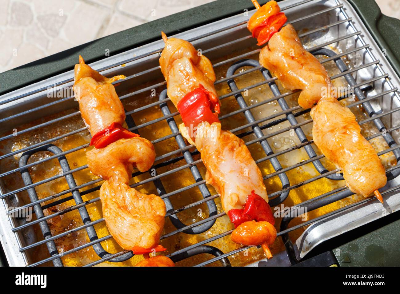 Marinierter Hähnchenbrochette auf dem Gitter eines elektrischen Grills Stockfoto