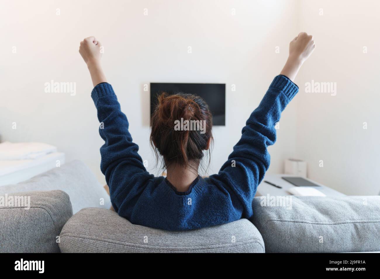 Aufgeregt, glücklich moderne Frau beobachten WM Fußballspiel, Meisterschaft auf der Couch zu Hause. Sport, Fernsehen, Spaß haben. Stockfoto