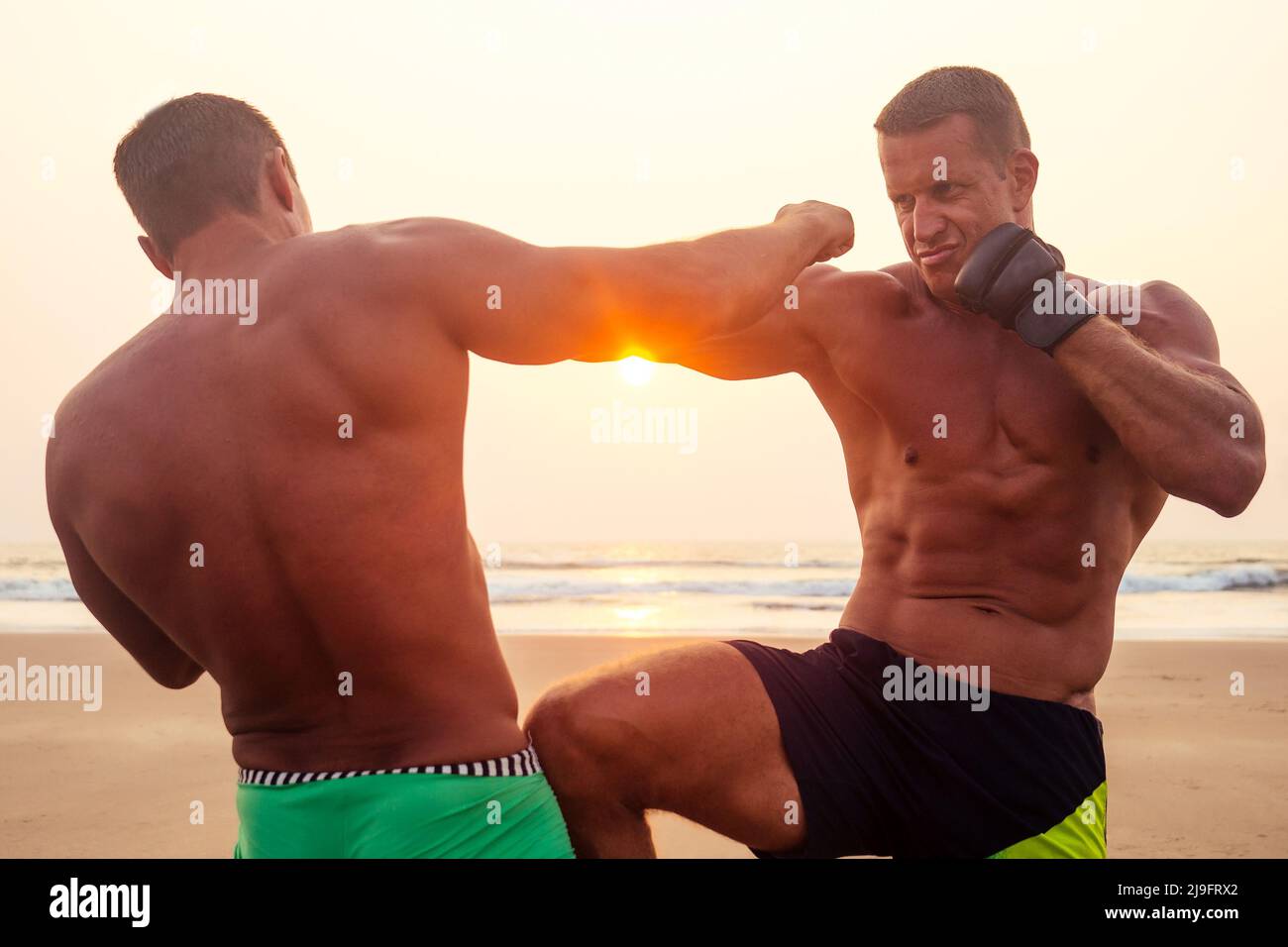 Starker Boxer Mann während Kickboxen Übung Kampf mit Trainer bei Sonnenuntergang tun .schließen Porträt von gut aussehenden Fitness männlichen Modell Bodybuilder Wut, Wut Stockfoto