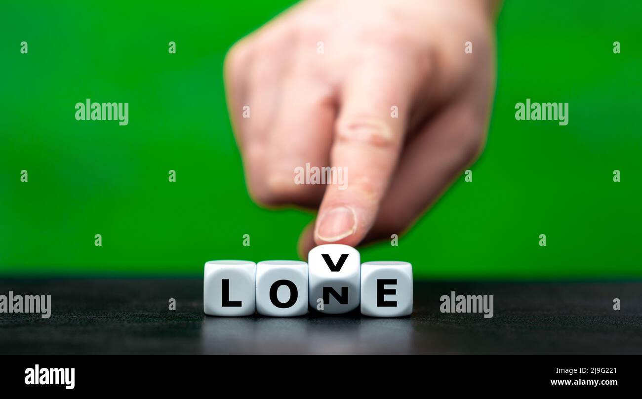 Hand dreht Würfel und ändert das Wort Lone zu lieben. Stockfoto