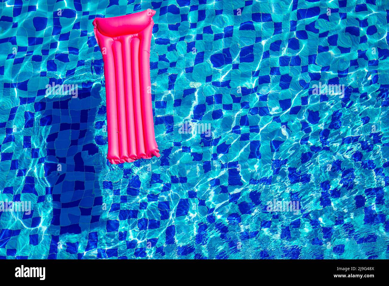 Pinke aufblasbare Matratze auf blau türkisfarbenem Wasser Swimmingpool kopieren Raum Draufsicht Stockfoto