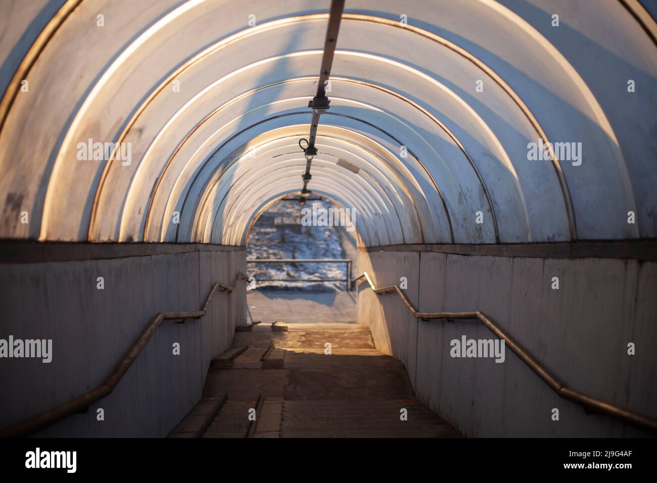 Fußgängertunnel zum Überqueren der Straße. Ein runder Tunnel, der sich in die Ferne erstreckt. Weiche Farben und sich wiederholende Elemente in Form von Bögen. Ur Stockfoto