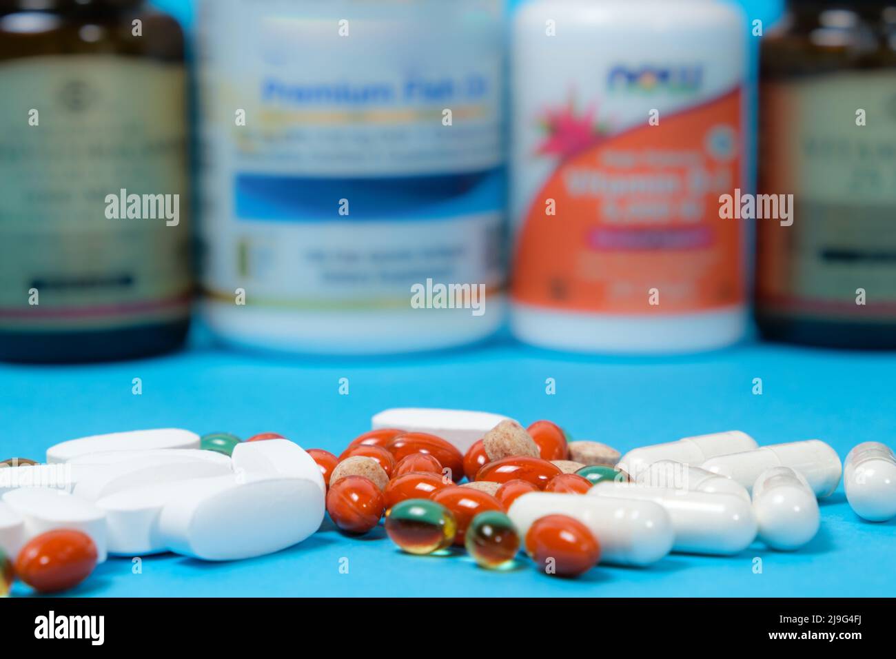 Weiße und orangefarbene Kapseln und Pillen auf blauem Hintergrund, Gläser mit Nahrungsergänzungsmitteln auf dem Hintergrund Stockfoto