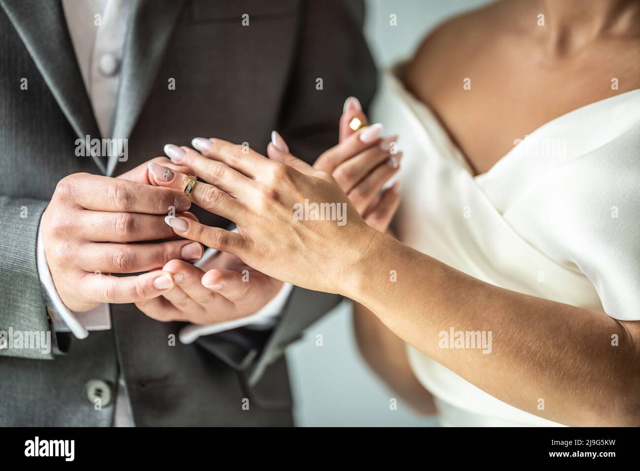 Das Brautpaar tauscht Ringe aus, während der Bräutigam einen Ring auf den Finger einer Braut legt. Stockfoto