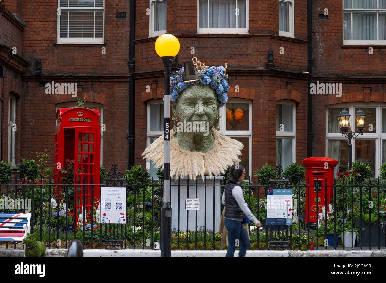 Lower Sloane Street, London, Großbritannien. 23 Mai 2022. Der Sommeranfang wird mit einem Besuch in Chelsea in Bloom gefeiert, Chelseas jährlich stattfindende Blumenkunstausstellung und Londons größtem, kostenlosen Blumenfestival, das zeitgleich mit der RHS Chelsea Flower Show stattfindet. Bild: Porträt der Königin mit traditionellen britischen Ikonen - rote Telefondose und rote Briefkasten - außerhalb der Sloane. Quelle: Malcolm Park/Alamy Live News Stockfoto