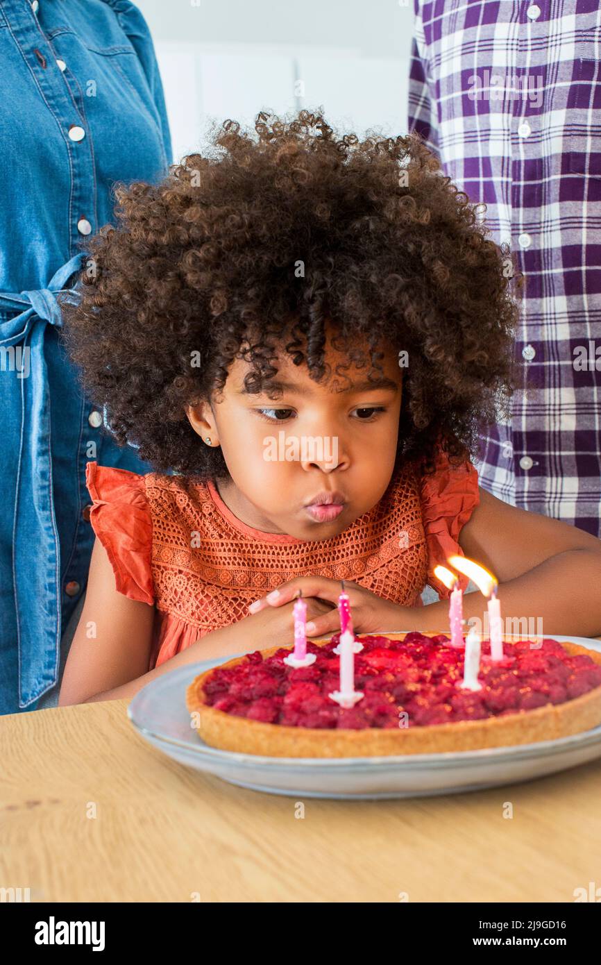 Mädchen bläst Kerzen auf Kuchen Stockfoto