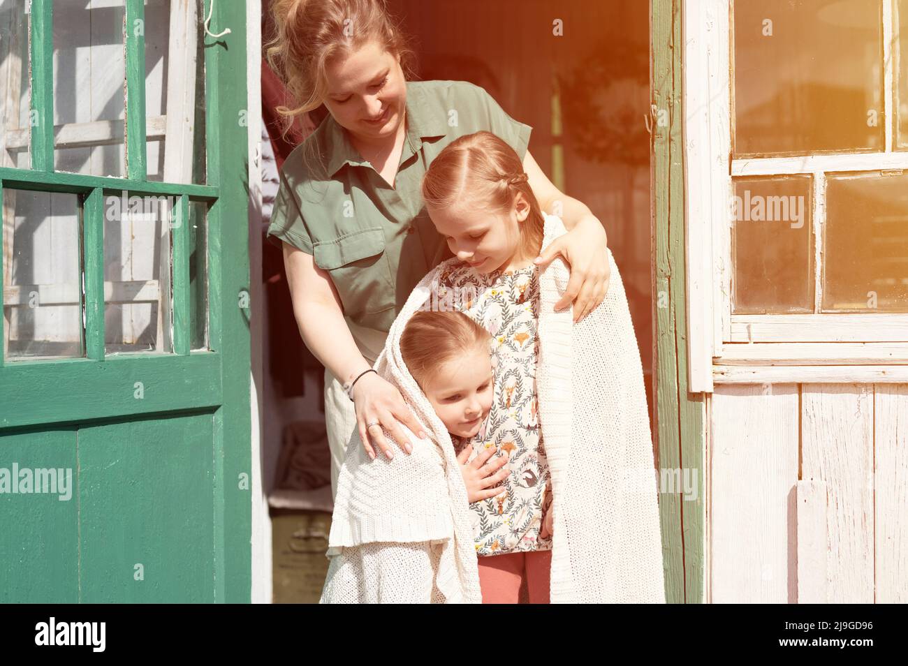 Glückliche Familie Mutter mit kleinen Kindern Töchter Helfer haben Spaß im Vorort Landleben am Waschtag. Ehrliche Mutter umarmen und Kinder mit Karli decken Stockfoto