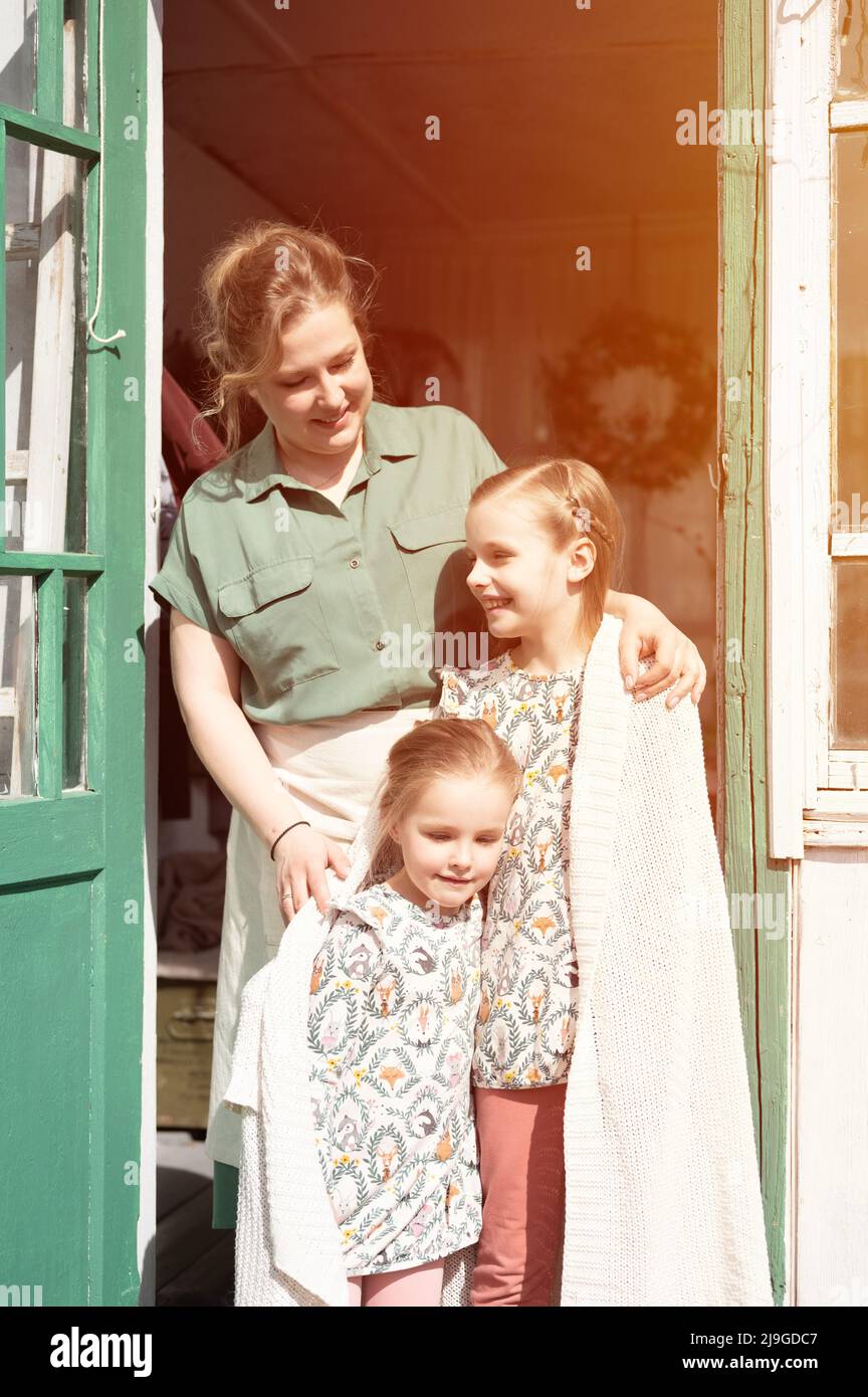 Glückliche Familie Mutter mit kleinen Kindern Töchter Helfer haben Spaß im Vorort Landleben am Waschtag. Ehrliche Mutter umarmen und Kinder mit Karli decken Stockfoto